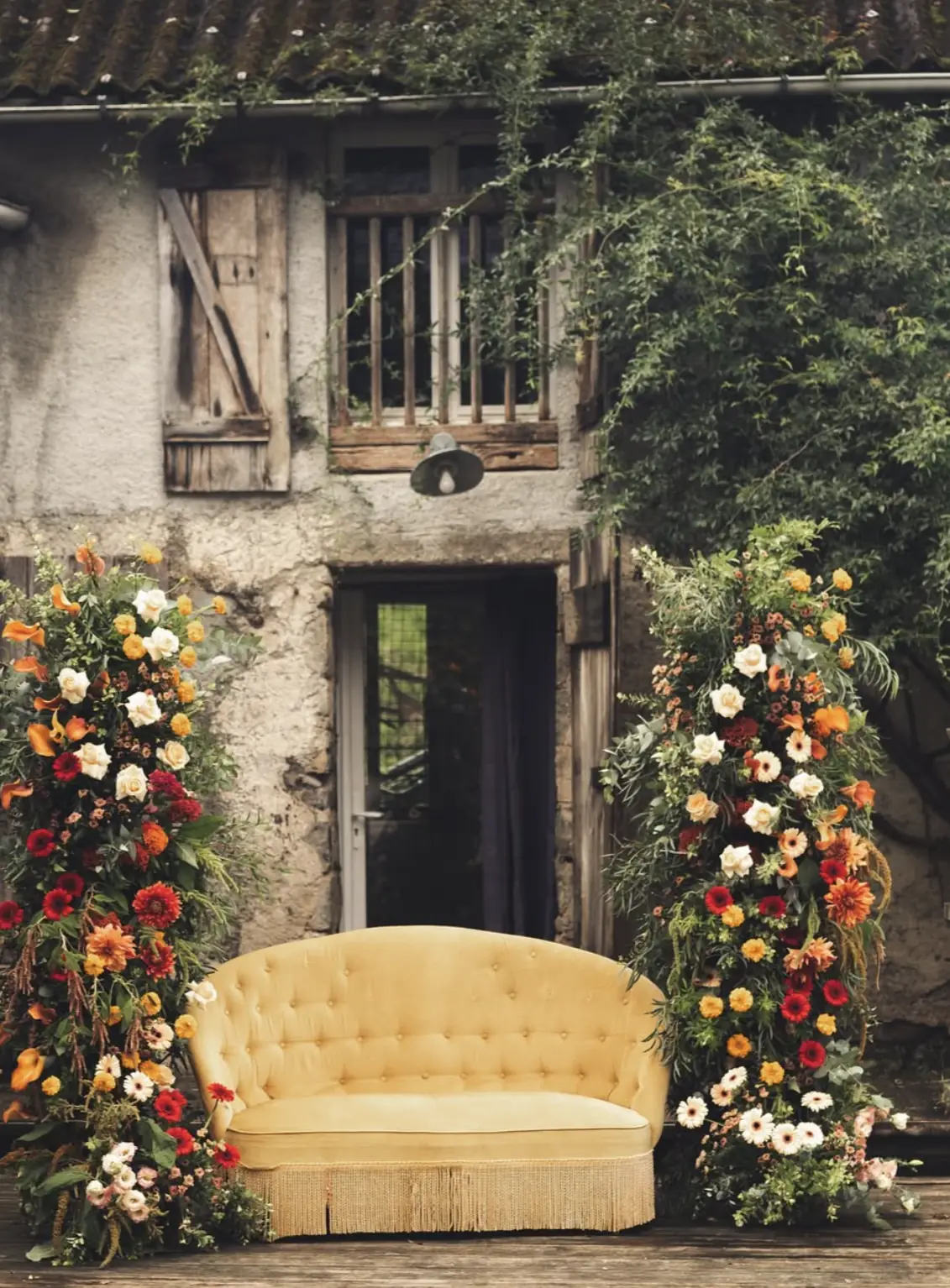 Arches florales encadrant la porte de grange en pierre lors d'un mariage à Passiflorart