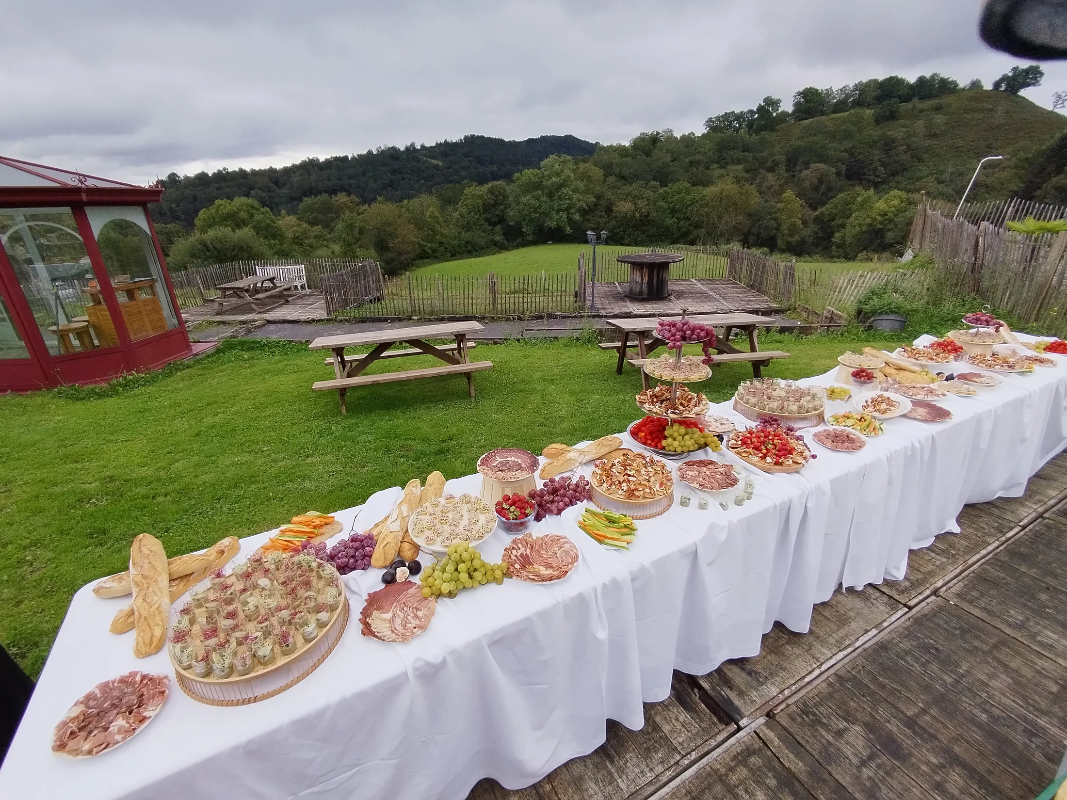 Le buffet dressé dehors sur une longue nappe blanche, face à la prairie