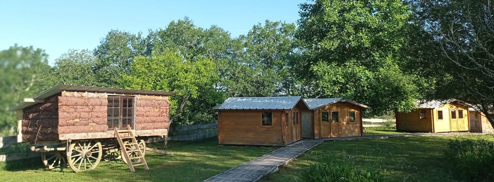 Les chalets et la roulotte du gîte, alignés au bord de la prairie