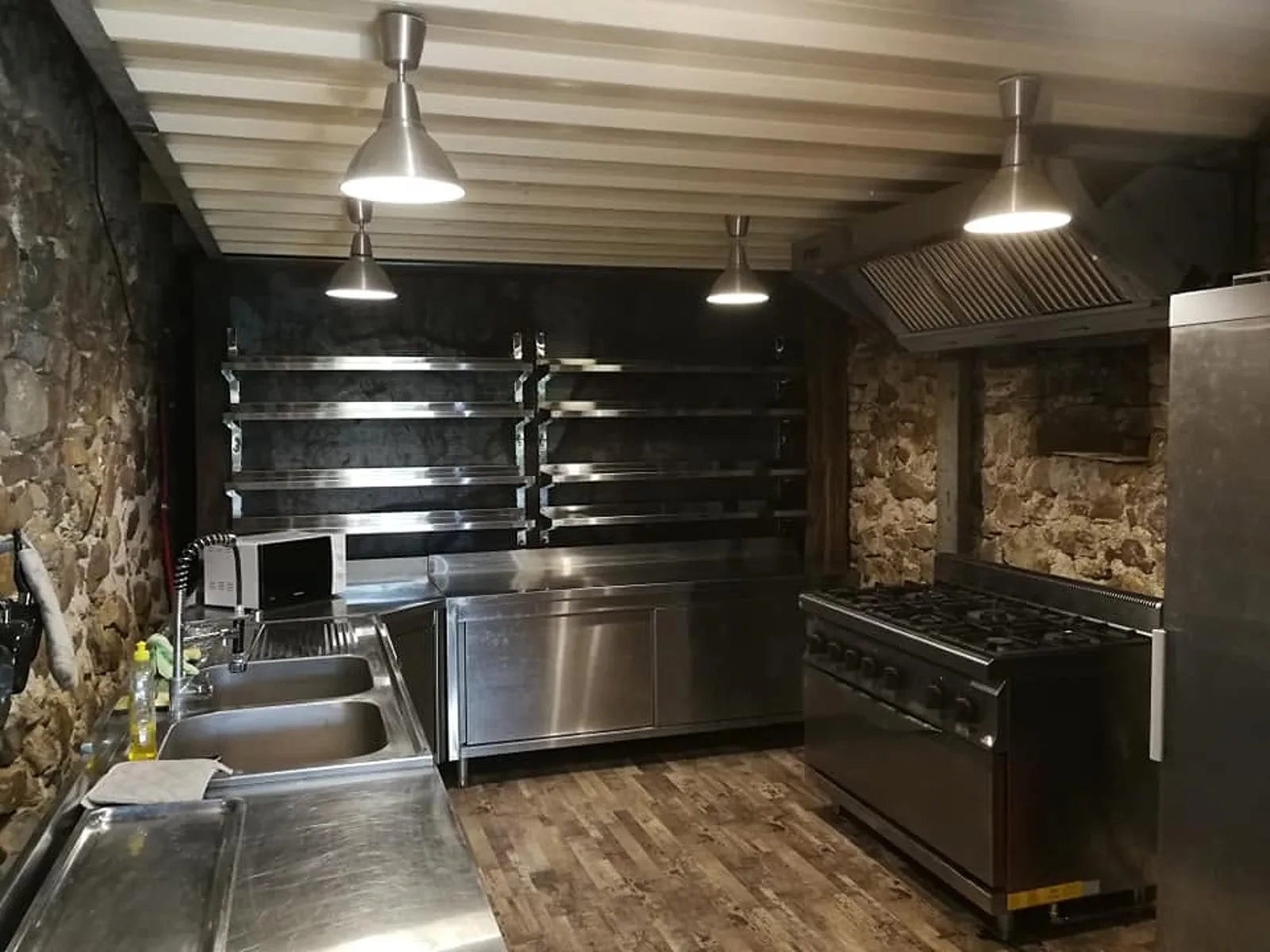 La cuisine professionnelle du domaine, son piano de cuisson et ses murs en pierre