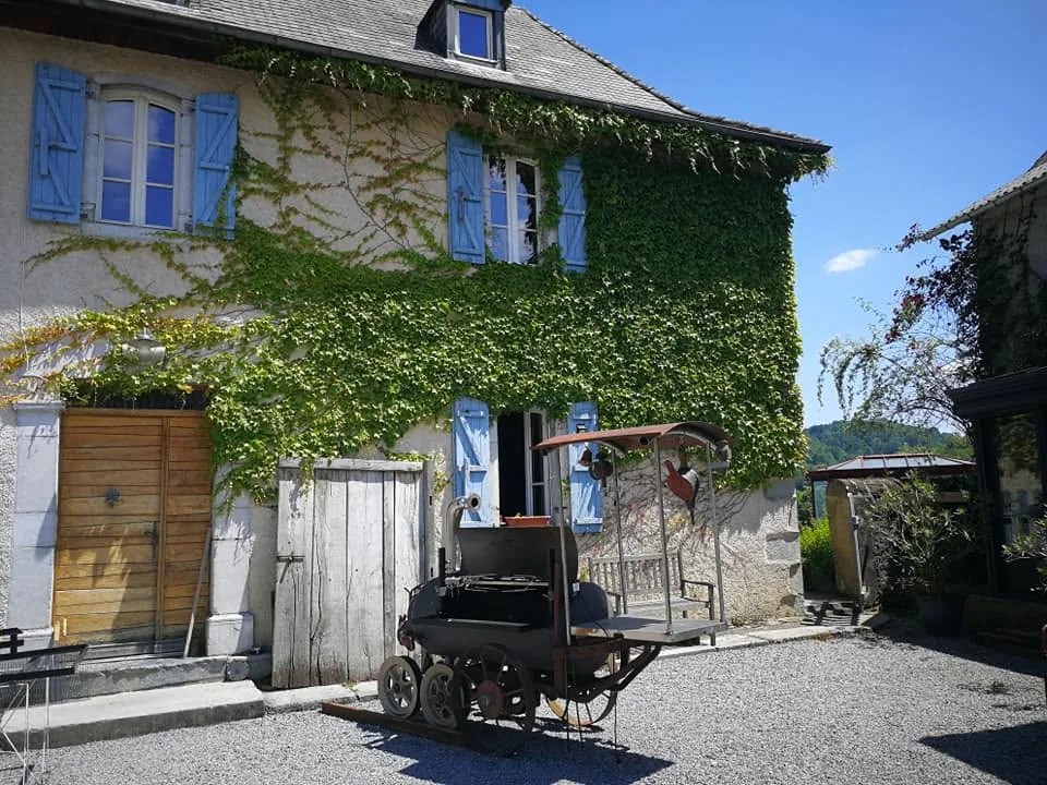 Façade en pierre du domaine, son lierre et ses volets bleus