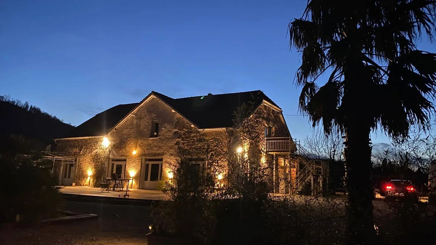 Le bâtiment du gîte éclairé à la tombée de la nuit