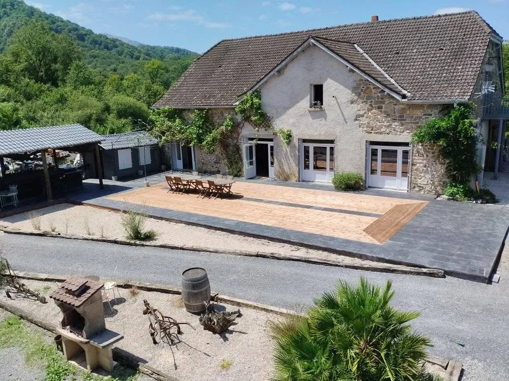 Cour aménagée du domaine, sa terrasse en bois et sa table dressée