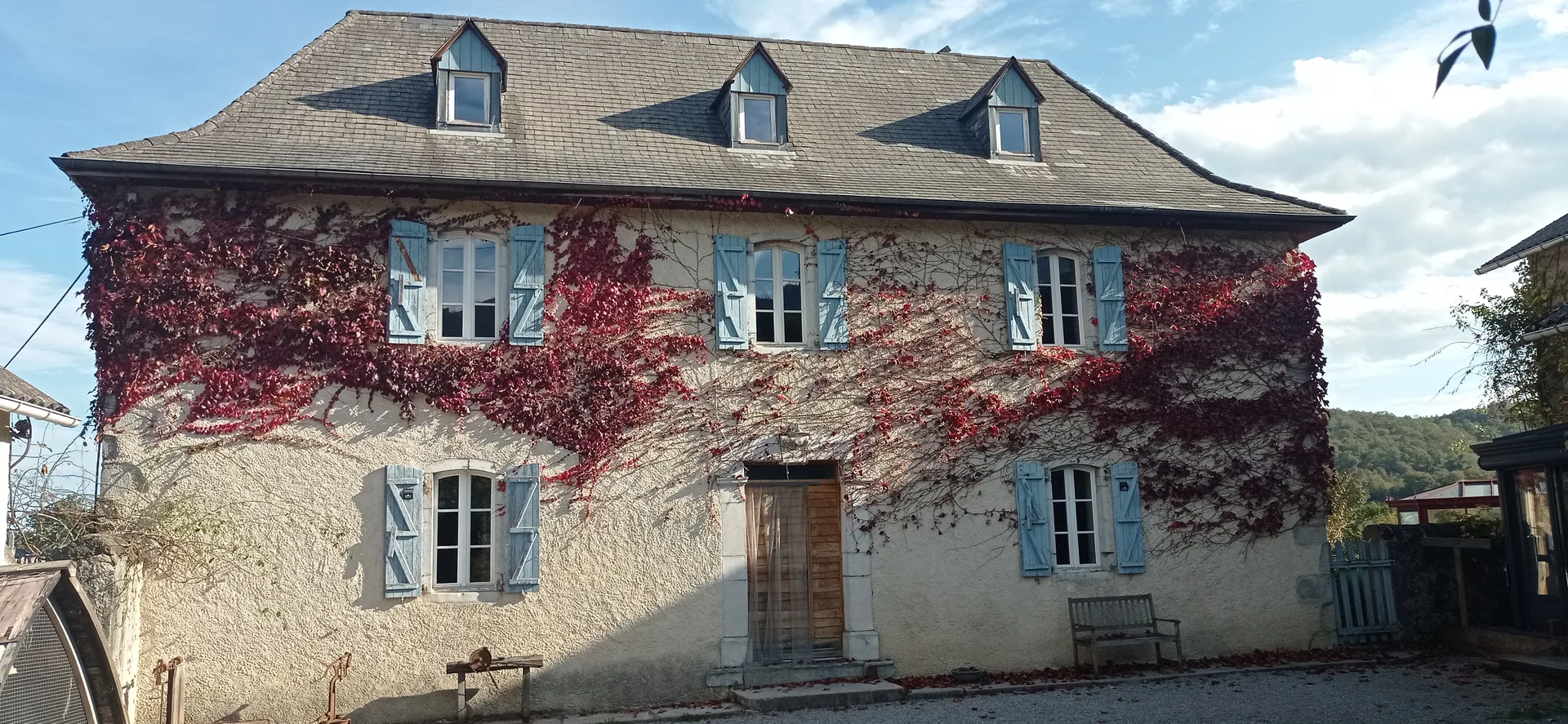 Façade de la maison béarnaise du domaine, couverte de vigne vierge rouge