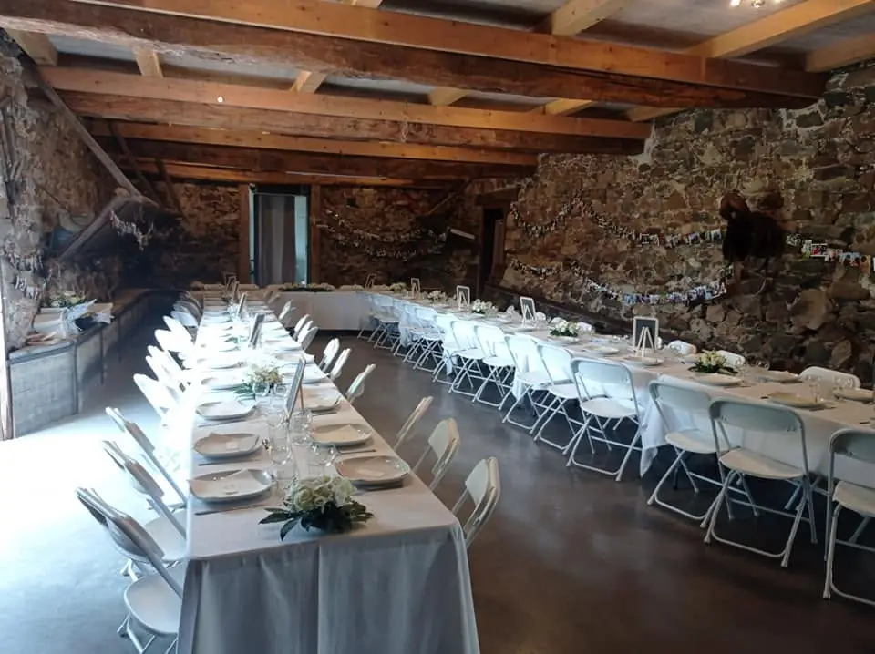 Grandes tablées dressées sous les poutres, dans la salle en pierre