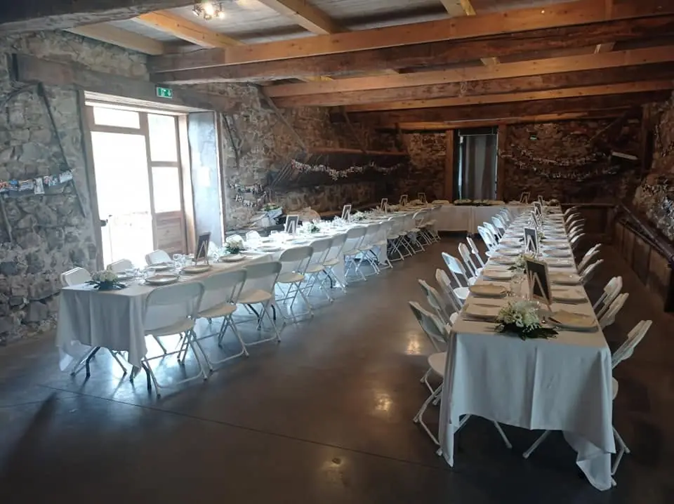 Salle en pierre du domaine dressée pour un repas, devant une grande fenêtre