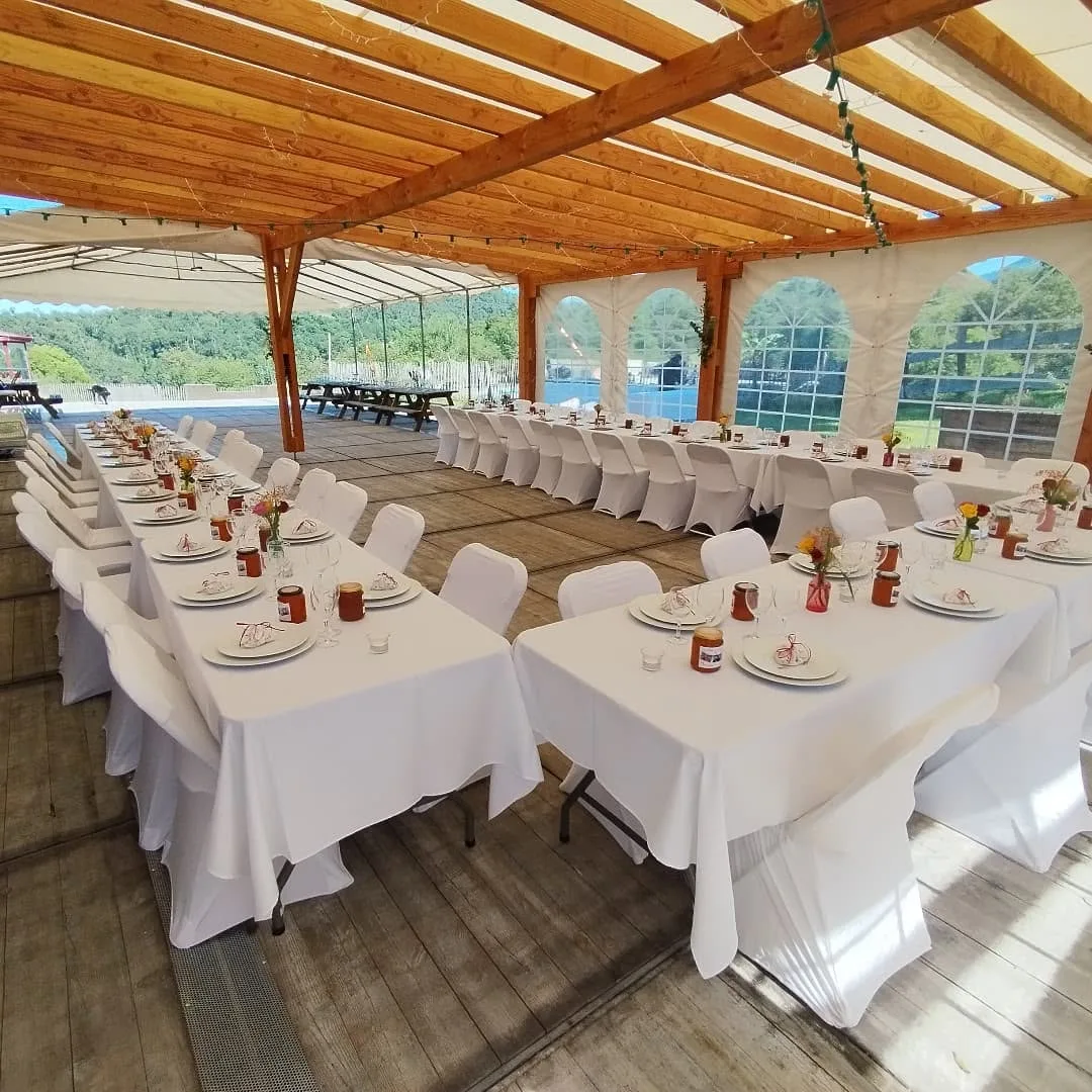 Tables dressées en nappes blanches sous la charpente du domaine